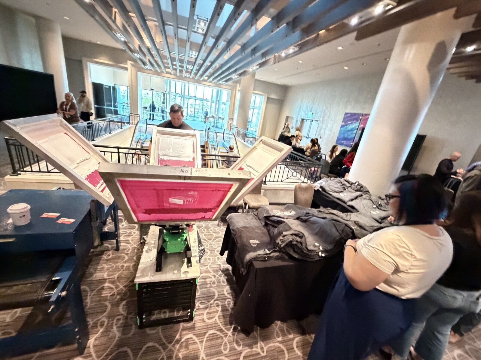 Guests gathered at a Merch Troop live printing activation watching a shirt being pressed